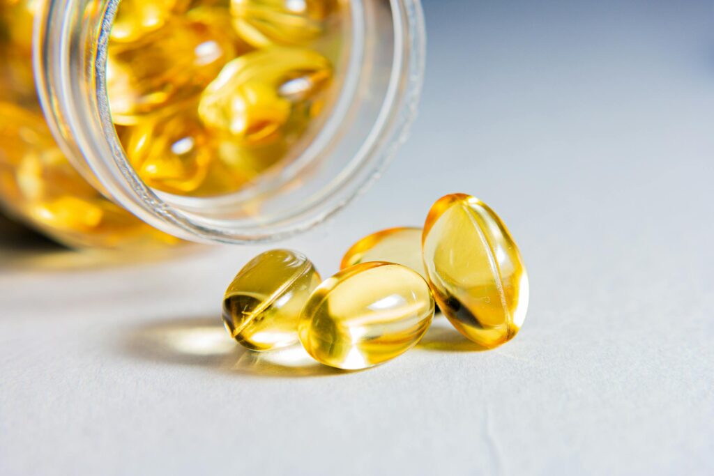 High-quality close-up of transparent softgel capsules spilled from a glass jar, showcasing vitamins or supplements.